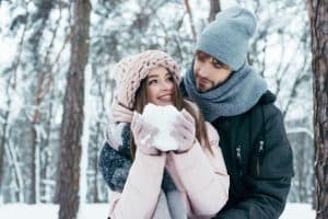 Young couple having fun together in snowy forest