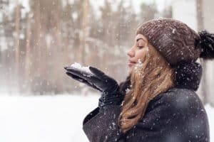 woman blowing on snow in winter