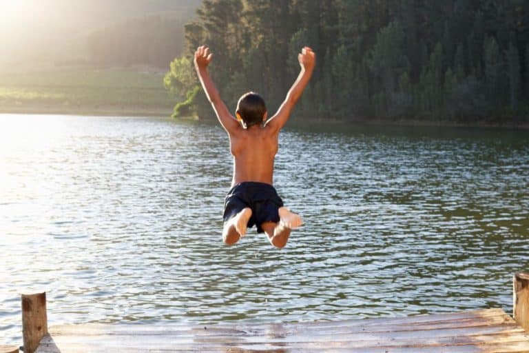 Young boy jumping into lake