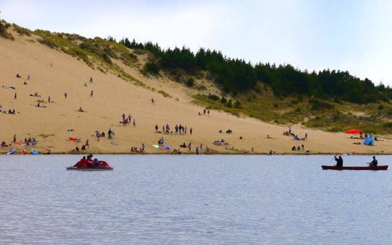 People playing on water and sand dunes at Jessie M Honeyman Memorial State Park