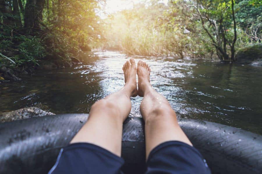 man floating down a river in a blow up tube