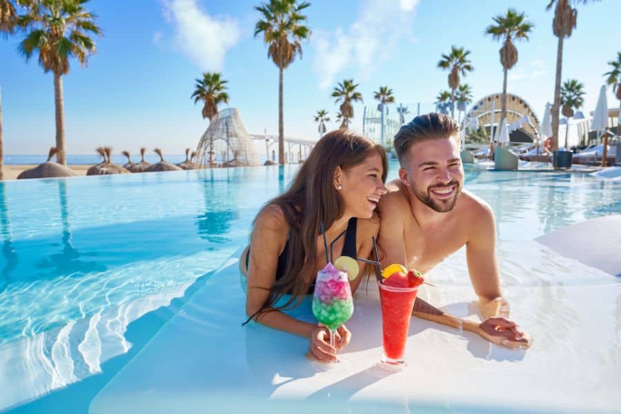 couple at all inclusive infinity pool with cocktails