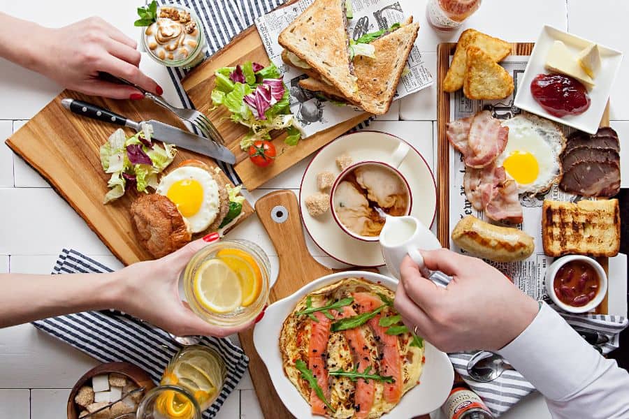 people reaching over a table full of brunch plates