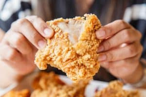 person holding Fried chicken and eating in the restaurant
