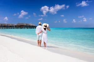 a couple in white standing at the shores of maldives