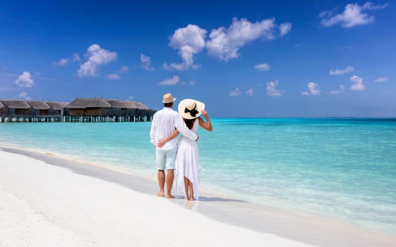 couple in summer clothing stands on a beach in Maldives