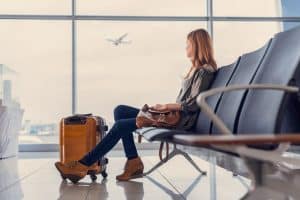 girl sitting with carry on and waiting to board plane