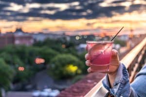 hand holding a pink alcoholic beverage rooftop bar
