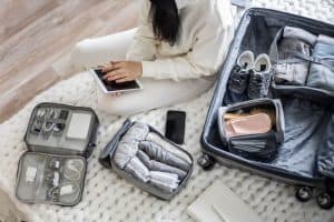 young girl sits on a bed packing luggage