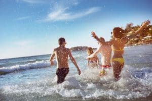 Happy friends running into the ocean water