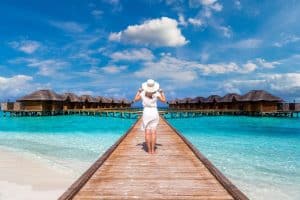 Woman standing on the wooden pier on a tropical island overwater bungalows