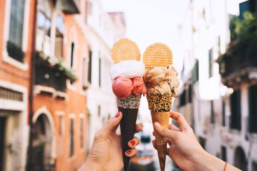 delicious italian gelato in waffle cone in front of streets and bridges of Venice
