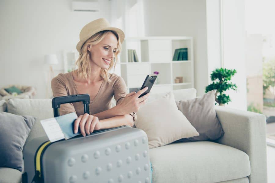 woman sitting on couch with luggage and looking at phone