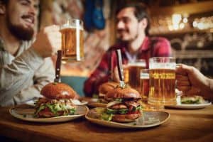 men at pub drinking beer and eating burgers