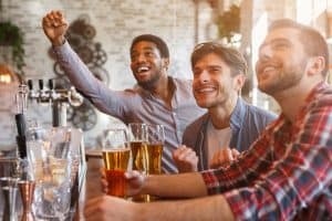 sports fans drinking beer celebrating victory at bar