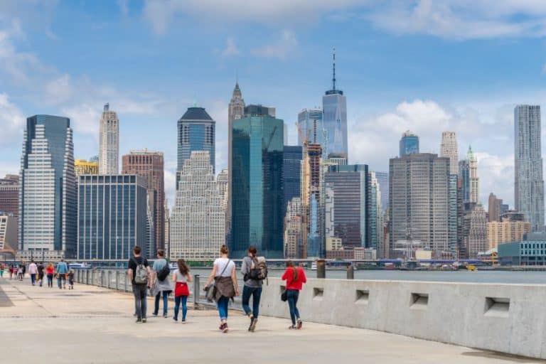 Tourists visiting the Brooklyn Bridge Park with Manhattan skyline in the background