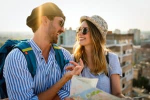 happy tourist couple on holiday holding paper map