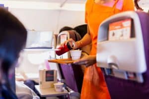 Flight attendant serving drinks to passengers on board plane