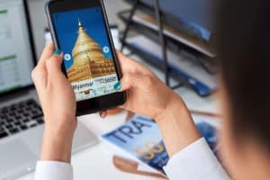 Woman browsing holiday deals destination vacation ideas screen with Myanmar temple