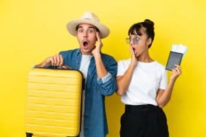 friends holding a suitcase and passport with surprise and shocked facial expression