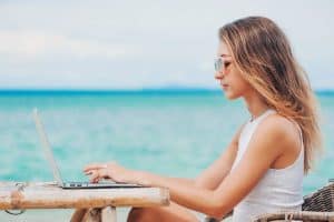 woman digital nomad using laptop on the beach