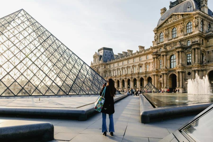 woman taking photo of the louvre in paris sp