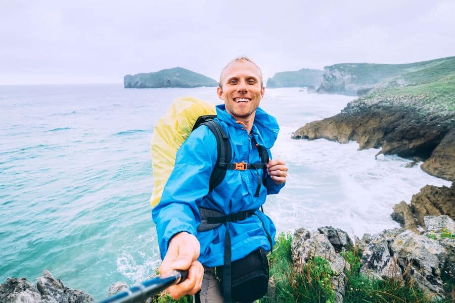 Smiling backpacker traveler take selfie photo on ocean coast