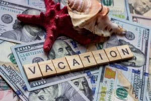 The word Vacation on dollar background with seashells