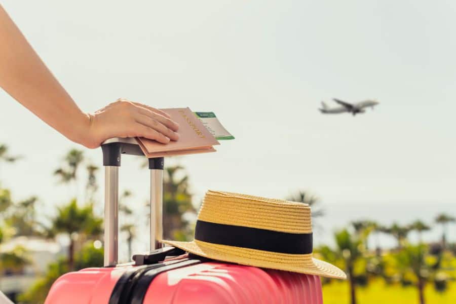 Woman with pink suitcase and passport with boarding pass