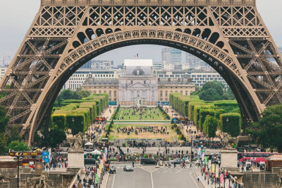 close up of eiffel tower with lots of tourists on foot