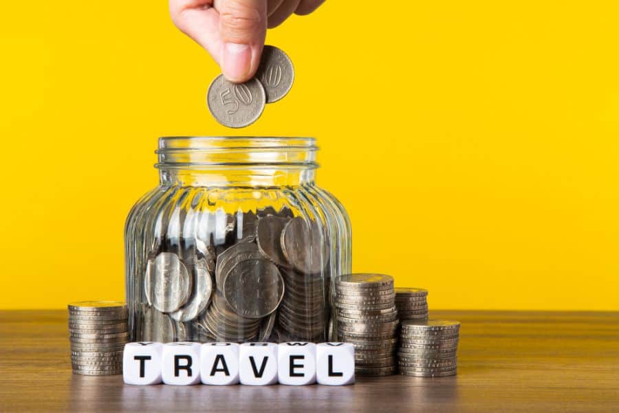 coins in glass money jar with yellow background