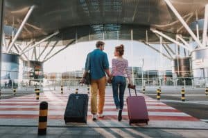 couple with travel suitcases holding hands in airport