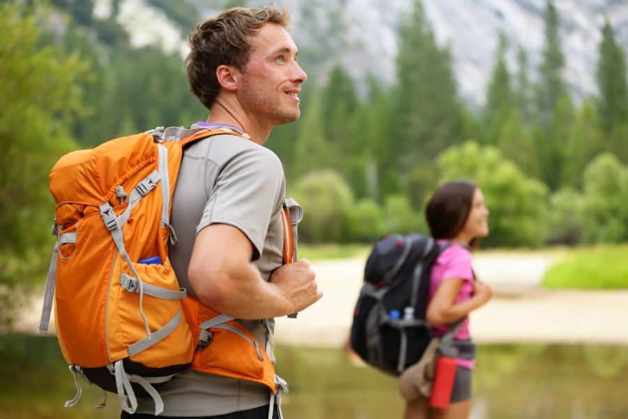 man and woman traveling with backpack