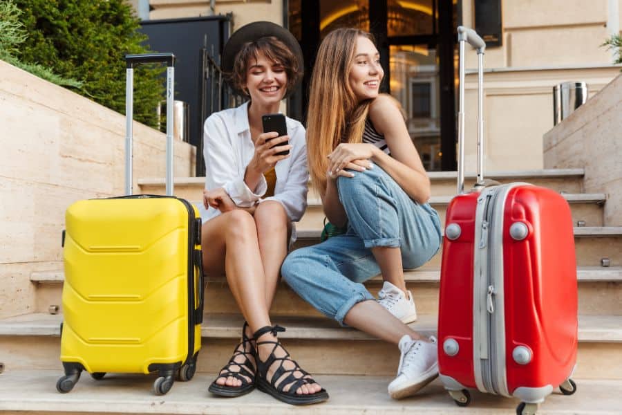 two women sitting on stairs with suitcases