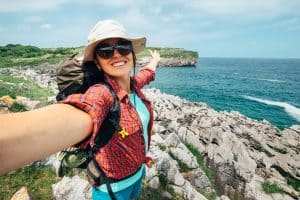 woman backpacker traveler take a selfie photo on amazing ocean coast