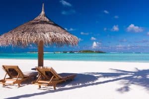 Chairs and umbrella on a beach with shadow from palm tree