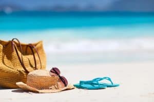 beach bag hat sunglasses and flip flops on tropical beach