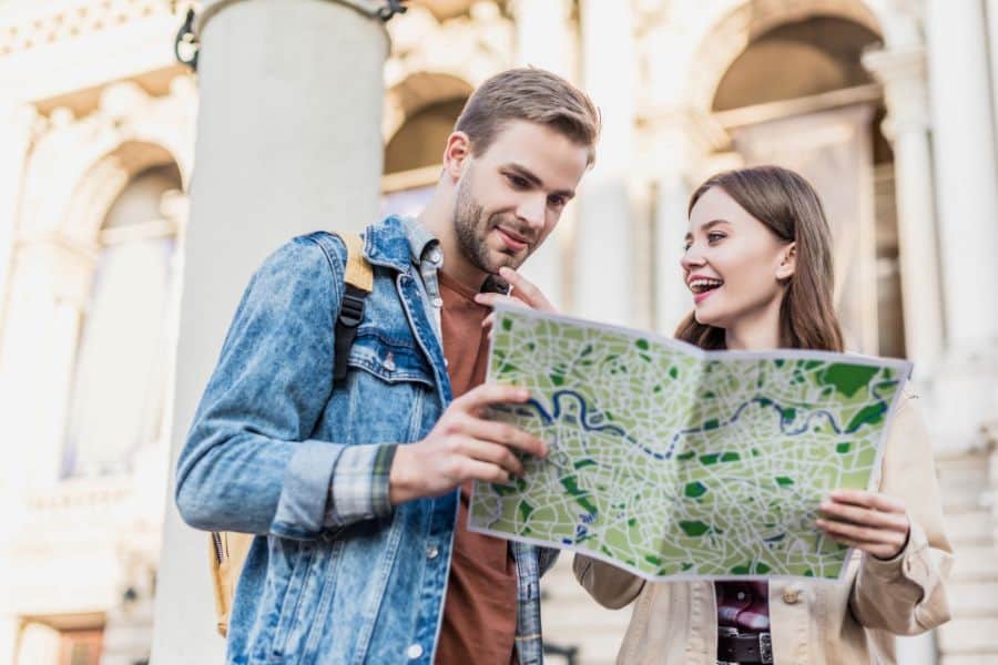 thoughtful boyfriend and happy girlfriend with map in city