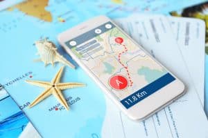 travel map app open on phone on top of a paper map