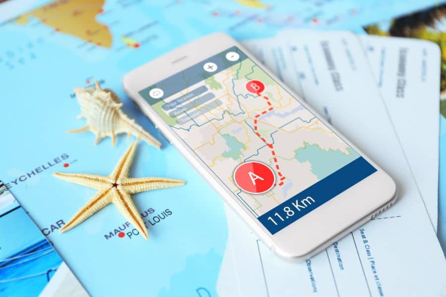 travel map app open on phone on top of a paper map