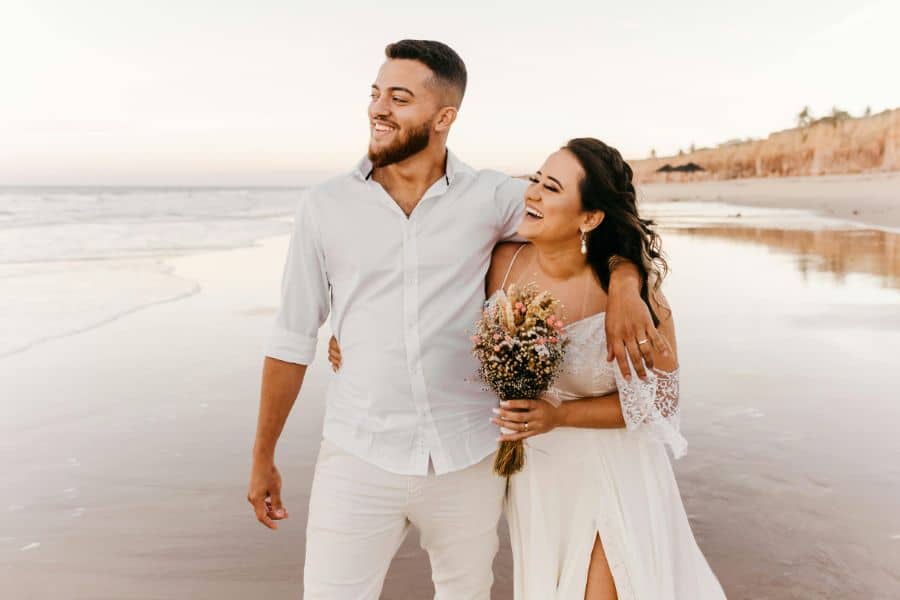 Delighted newlywed couple walking on beach sp