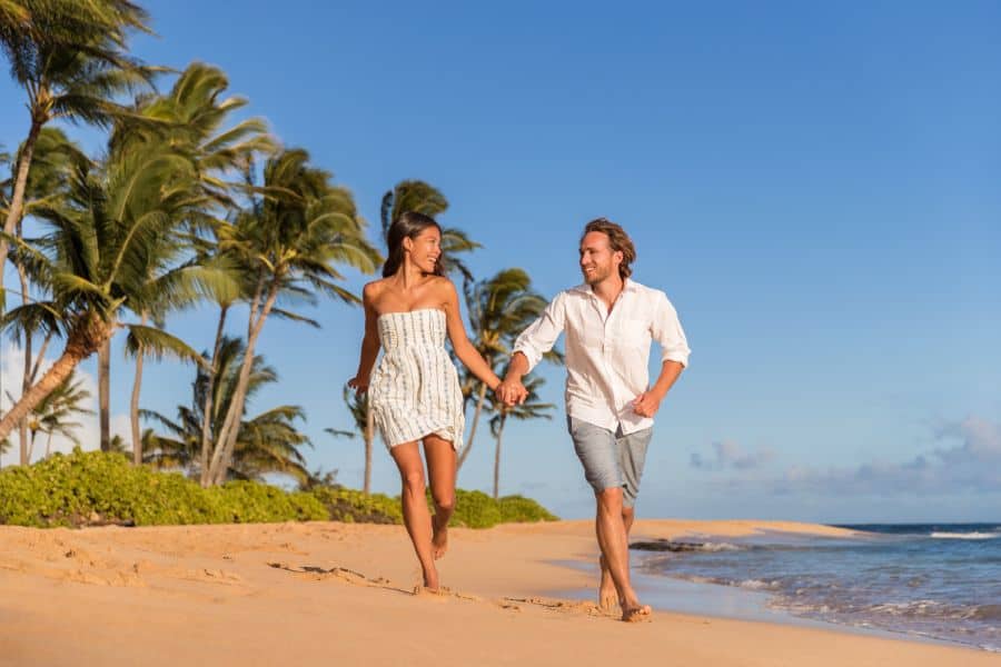 Happy couple running on the beach romantic getaway Waiohai Poipu in Kauai Hawaii