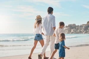 couple holding hands with their two children and walking along the beach