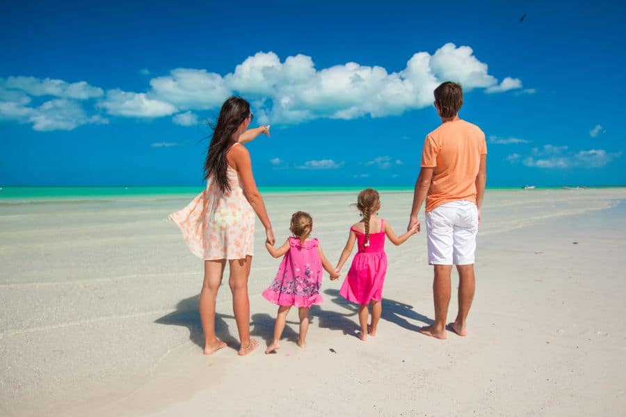 Back view family of four on caribbean beach vacation