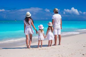 Back view of young family with two kids on caribbean vacation