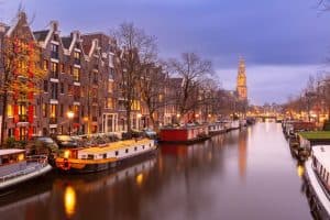 Night city view of Amsterdam canal Prinsengracht with houseboats and Westerkerk church Holland Netherlands