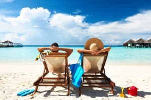 couple relaxing on a beach with overwater villas