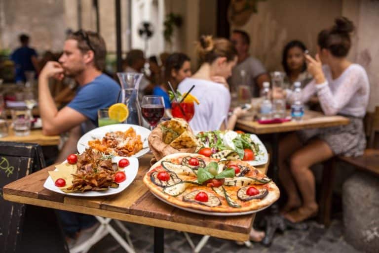 people eating traditional italian food in outdoor restaurant in Trastevere district in Rome Italy