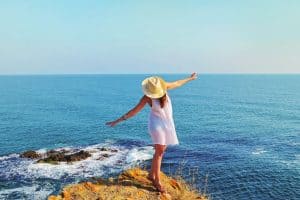 Happy Young Woman Solo Traveling on a Sea Beach with Black Sand